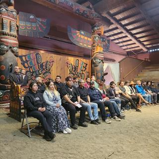 A group of students sits in a longhouse