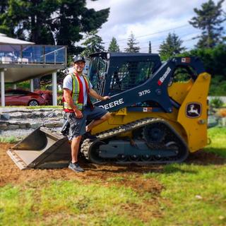 Jesse Anderson standing outside in front of one of his machines on a sunny day.