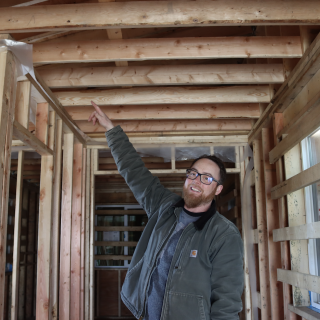 Program Instructor Andrew McLeod points to some of the work students have done inside the home