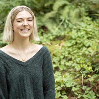 Denman Moody smiles while standing in front of green ferns.