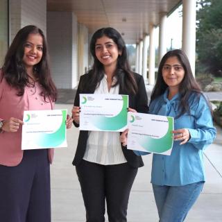 Three women hold certificates