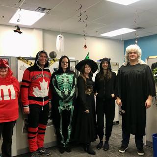 Six people in an office dressed up for Halloween. 