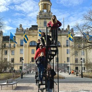 students pose on a slide in front of an old building