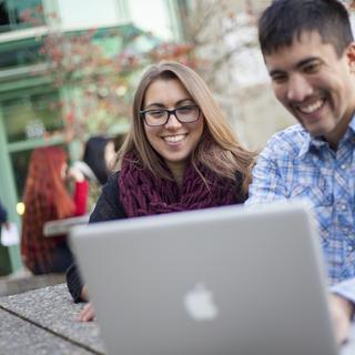 Two students look at a laptop screen together