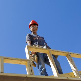 A carpenter up high building a frame