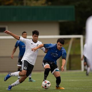 Mateo in the blue shirt runs down a soccer field with the ball pursued by an opposing player
