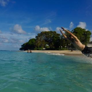 a person jumping into a very blue-green ocean