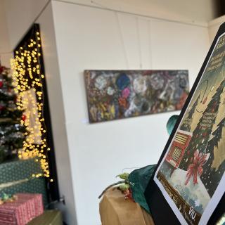 A Christmas Carol poster sits on a stand in front of a Christmas tree.