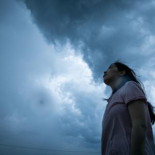 A woman stares up at a gray sky