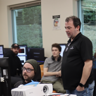 Information Technology and Applied Systems Instructor Brandon Britt observes carl belie on a project. 