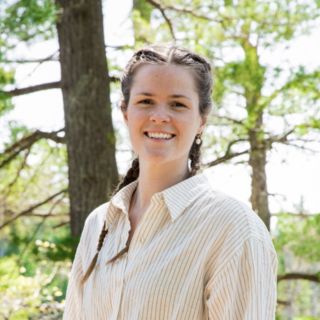 Laura Hutchinson smiling at the camera with trees in the background.