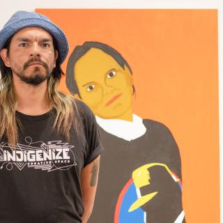 Atticus Mercredi stands in front of the painting of his mother.