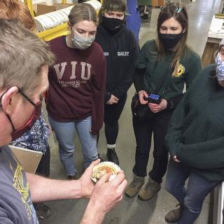 VIU students examine a scallop held by Provan Crump, from Coastal Shellfish Ltd.