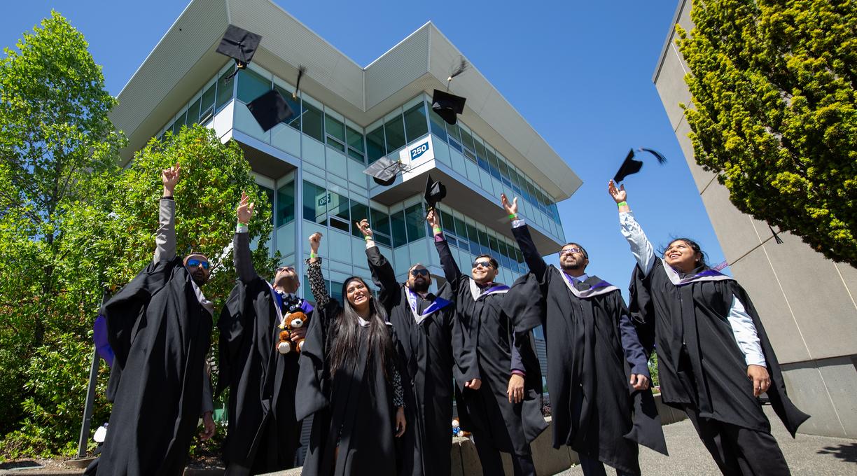 students in regalia throw their grad caps in the air