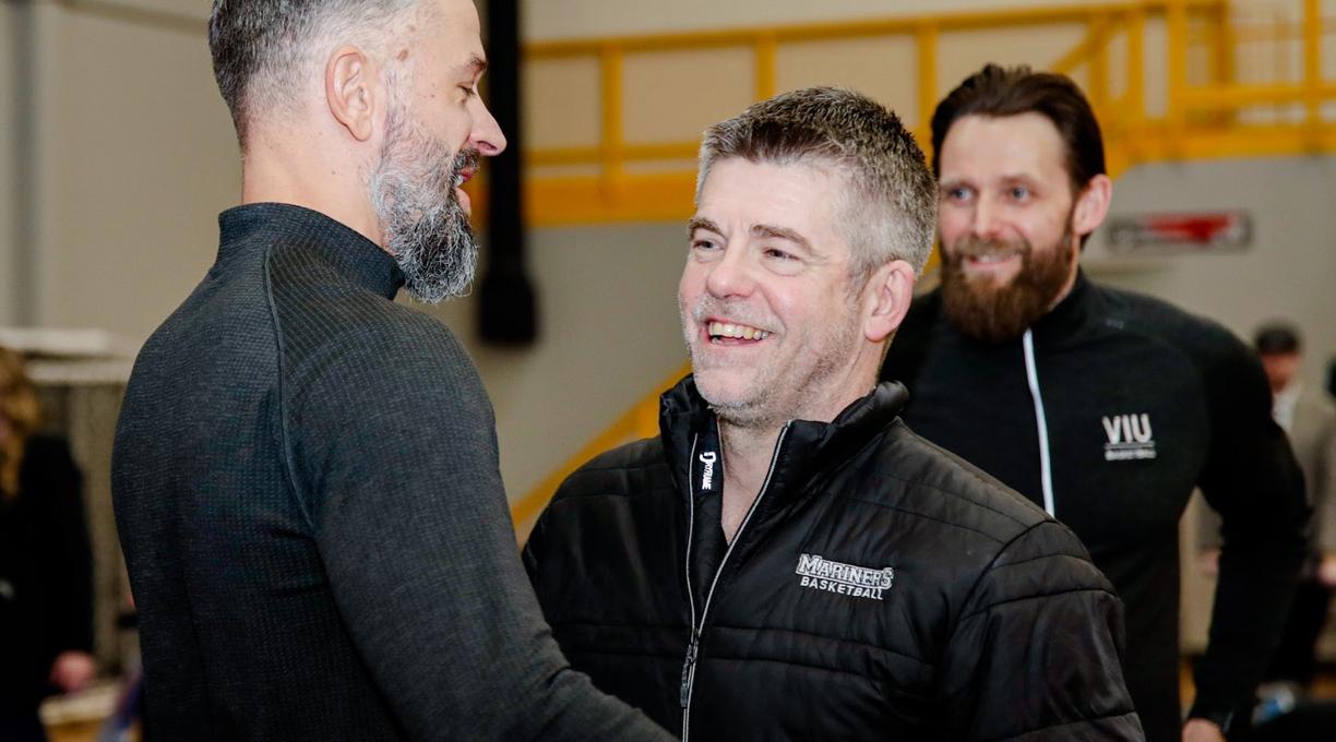 Two coaches lean in for an embrace