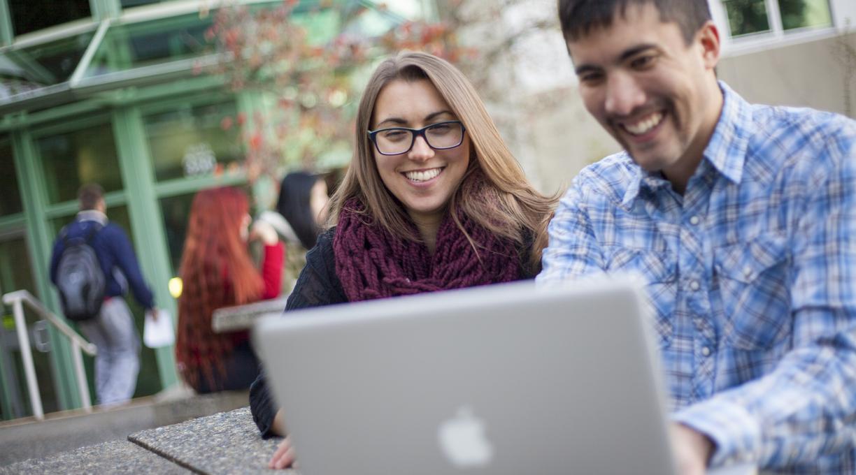 Two students look at a laptop screen together