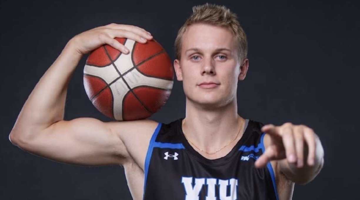 Kai Leighton in a Mariners jersey holding a basketball and pointing at the camera.