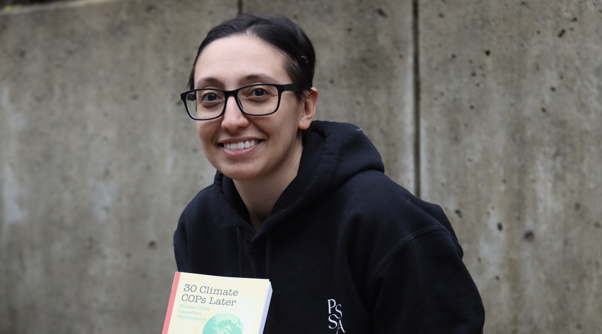 Lauren Touchant sitting outside and displaying her book and smiling at the camera.