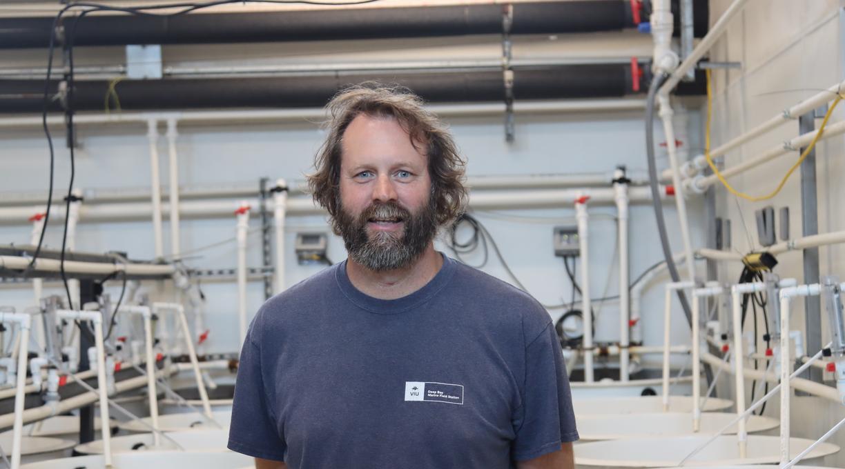 Tim Green standing in the tank room and looking at the camera at VIU Deep Bay Station
