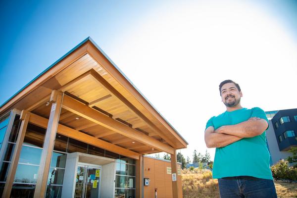 Hayden stands in front of Shq'apthut, VIU's Indigenous gathering place on the Nanaimo campus