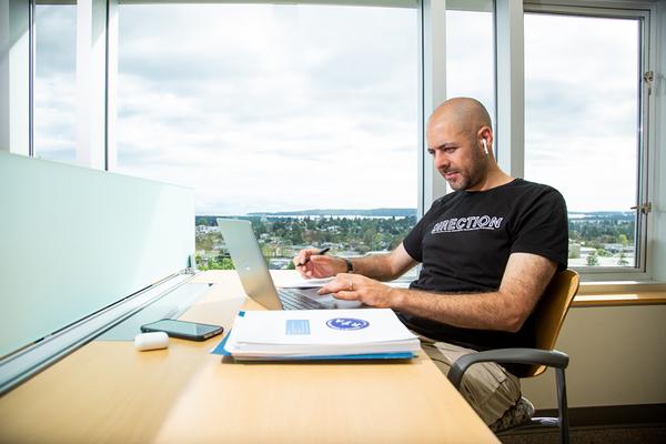 Student studies at a desk in the library with a view of the City of Nanaimo in the background