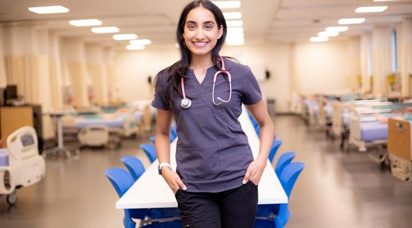 Ashley stands in VIU's nursing simulation lab, wearing scrubs and a stethoscope