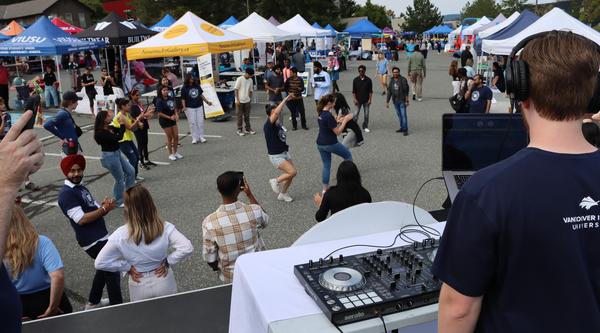 A DJ on a stage plays music while people dance in the background