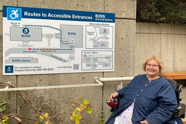 A woman poses beside a wayfinding sign at VIU's Nanaimo campus