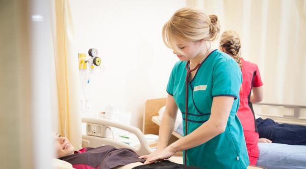 A nursing student practices on another nursing student