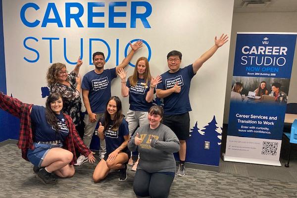 A group poses with the Career Studio sign and banner