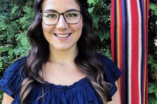 Cassidy Caron smiling with a Metis sash in background