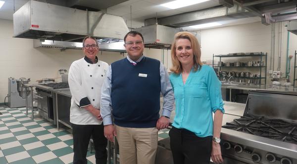 Three people stand in a culinary arts lab