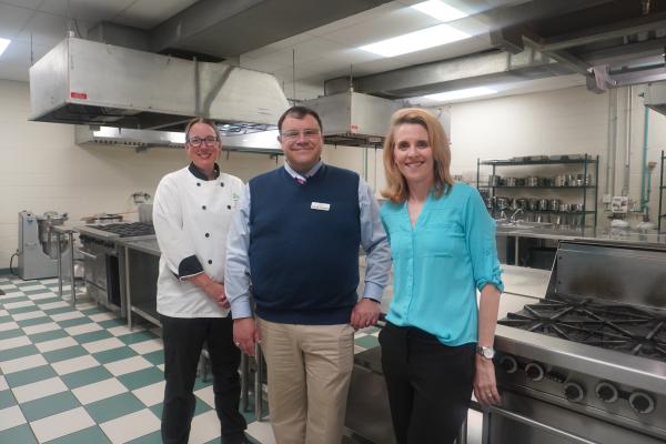 Three people stand in a culinary arts lab