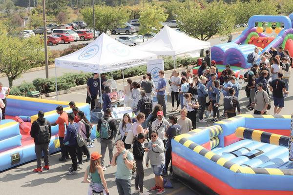 A crowded festival scene with tents and a bouncy castle