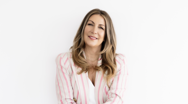 Jane Stoller sitting down against a white backdrop and smiling at the camera.