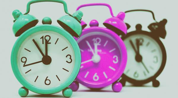 a picture of three small analog alarm clocks