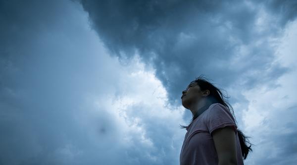 A woman stares up at a gray sky