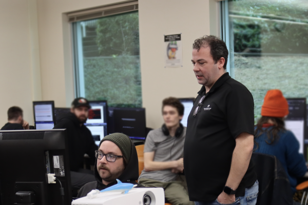 Information Technology and Applied Systems Instructor Brandon Britt observes carl belie on a project. 