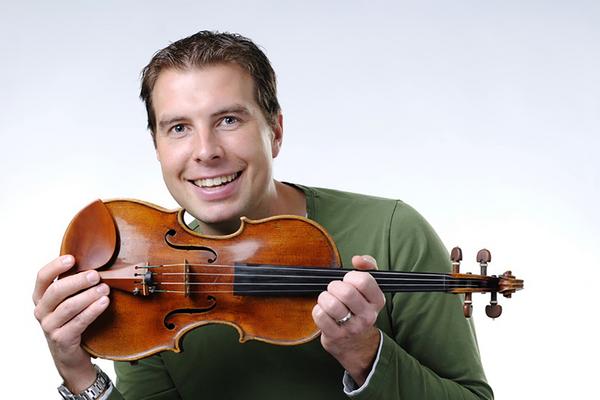 James Mark smiles while holding a violin.