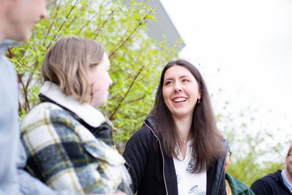 A young woman with long dark hair laghing with friends.