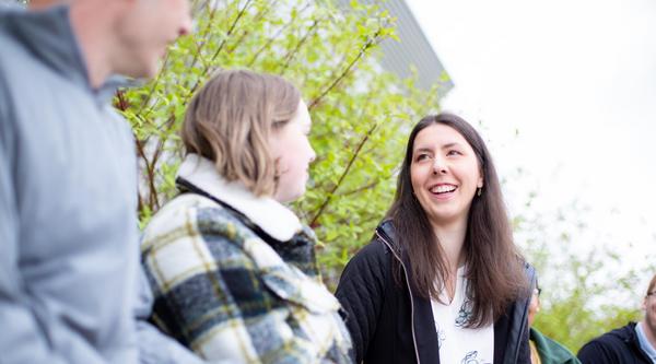 A young woman with long dark hair laghing with friends.