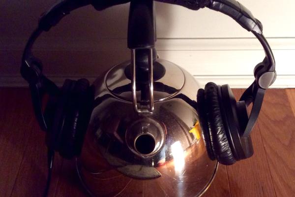 Headphones resting on a tea kettle.