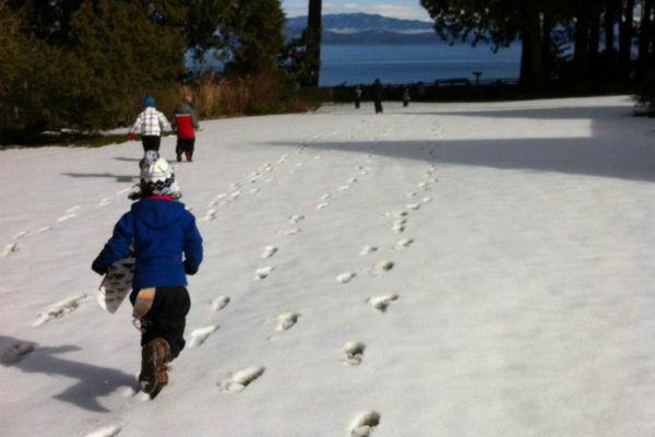 Children running across a snowy lawn