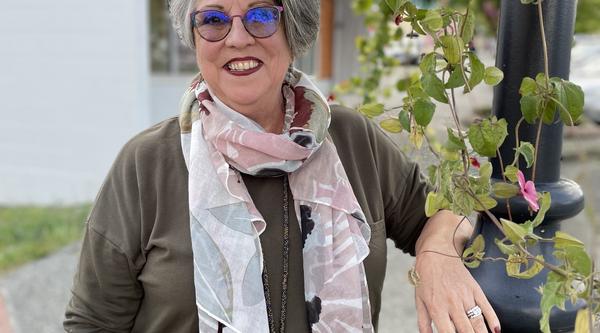 Mary Clare stands next to a lamppost with flowers trailing down it