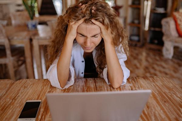 Woman stares at a laptop screen, head in her hands