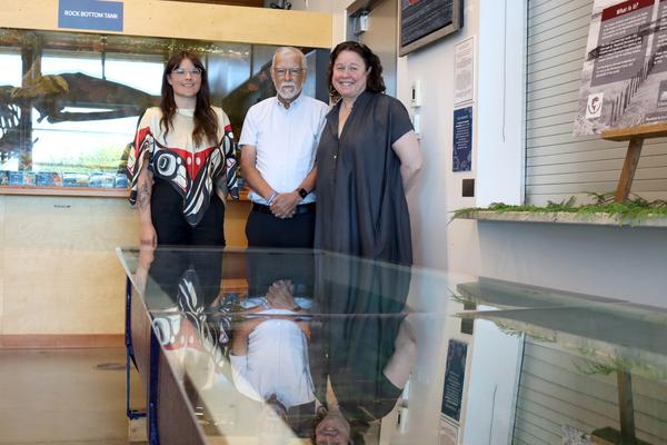 Three people pose with a tank