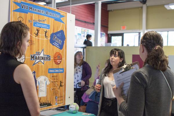 Three students examine a research poster at CREATE.