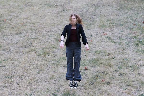 Samantha jumping in a field of scraggly grass