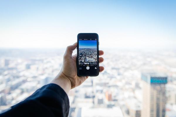 person holding cellphone out to take a picture of a city view