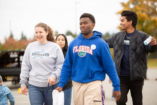 Four students walk together with festival in background